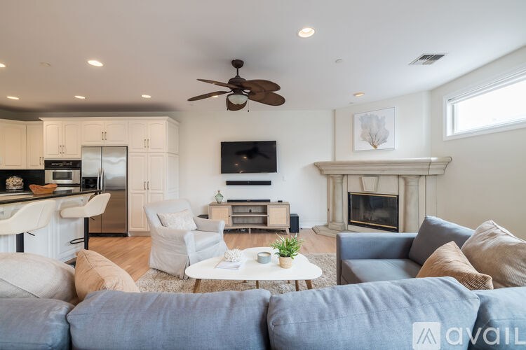 A living room with a grey couch and a white ceiling fan.