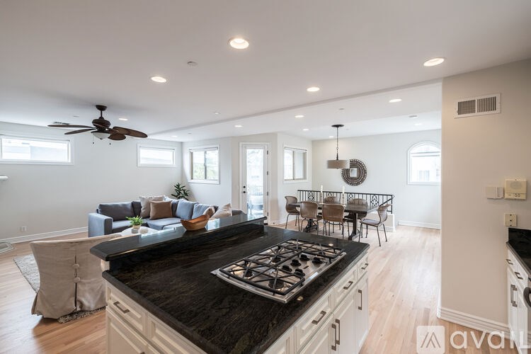 A modern kitchen with a black countertop and a ceiling fan.