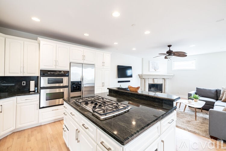 A modern kitchen with a black granite countertop and white cabinets.