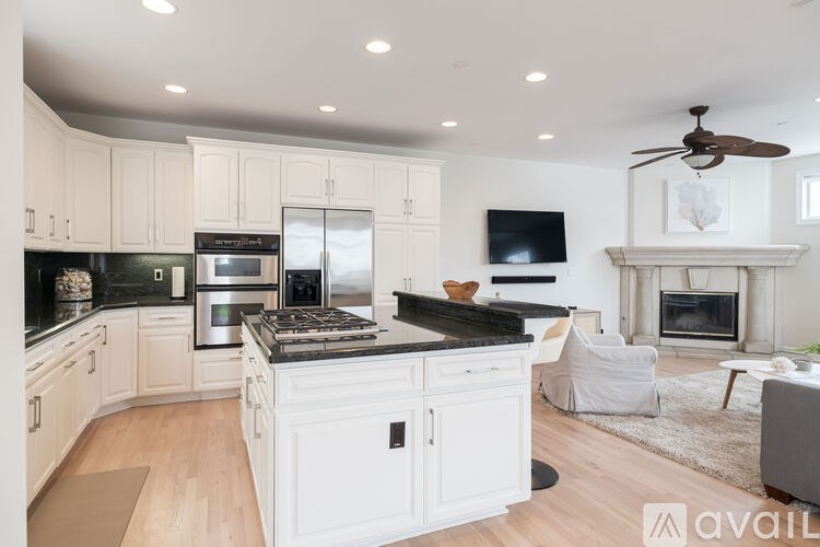 A modern kitchen with white cabinets and a black countertop.