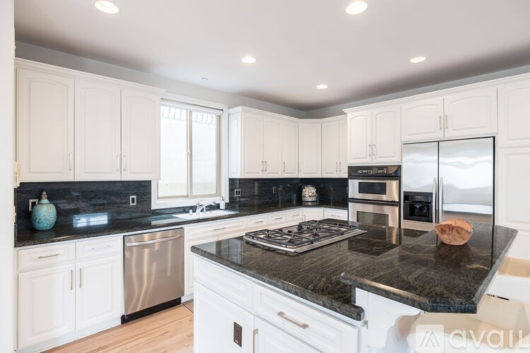 A kitchen with white cabinets and a black countertop.