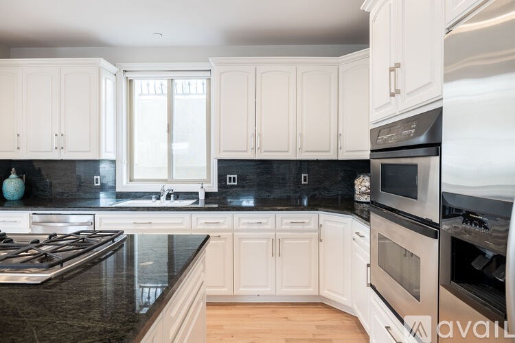A kitchen with white cabinets and black countertops.