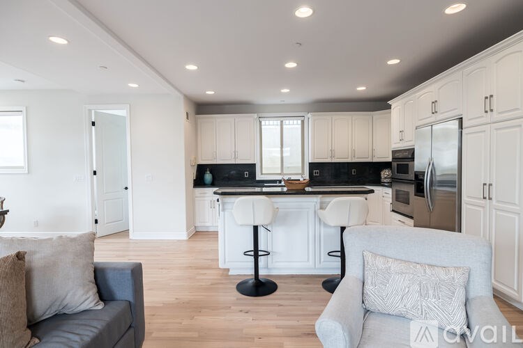 A modern kitchen with a bar stool and a grey couch.