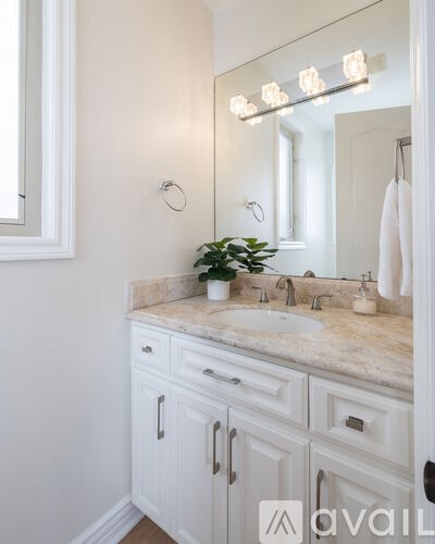 A bathroom with a marble countertop and white cabinets.