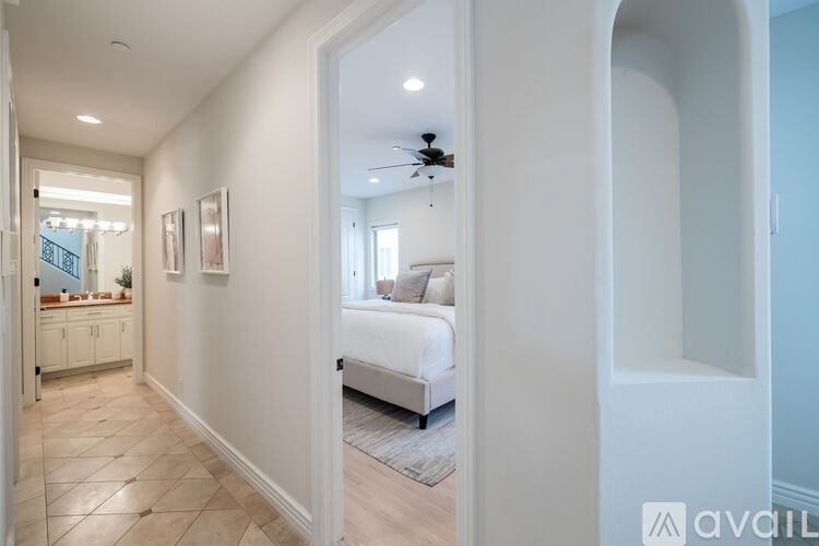 A bedroom with a bed, a ceiling fan, and a mirror.