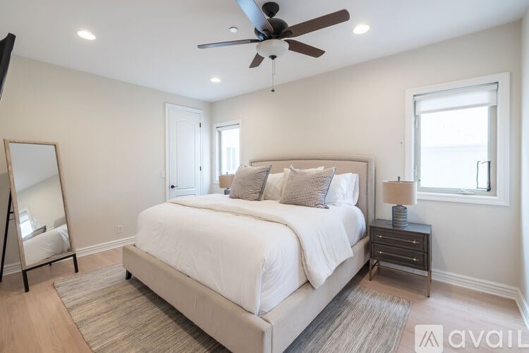 A bedroom with a large bed, a ceiling fan, and a window.
