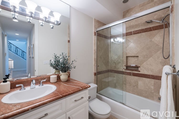 A bathroom with a marble countertop and a walk-in shower.