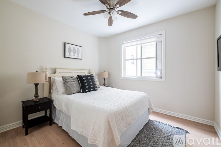 A bedroom with a bed, nightstand, and window.