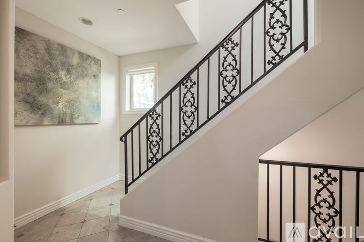 A staircase with a black railing and a painting on the wall.