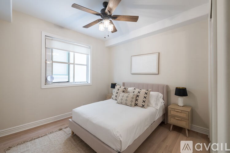 A bedroom with a bed, a ceiling fan, and a window.