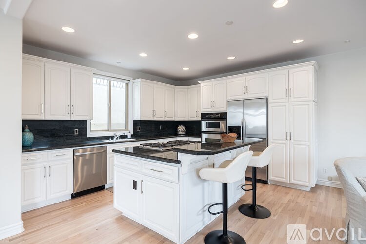 A modern kitchen with white cabinets and a black countertop.