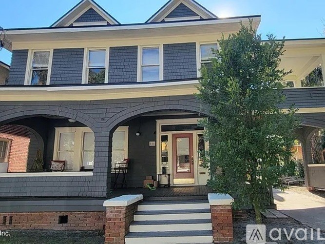 A house with a front porch and a tree in front.