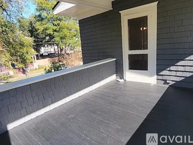A grey house with a white door and steps leading up to it.