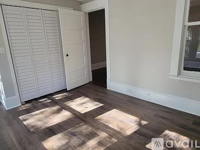 A room with a white door and a window with white blinds.