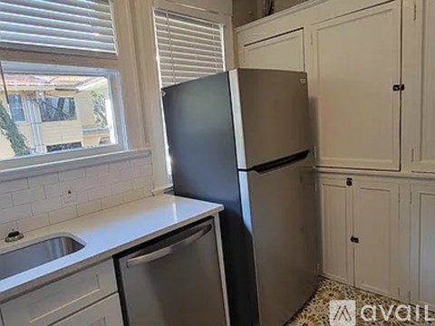A kitchen with a black refrigerator and a stainless steel dishwasher.