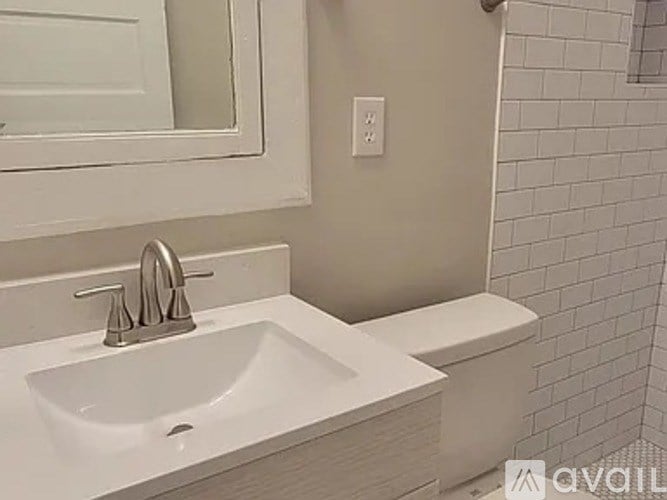 A white sink with a silver faucet is on a white countertop.