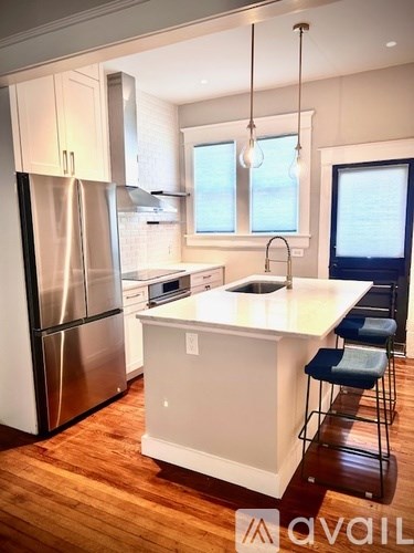 A modern kitchen with a white island and stainless steel appliances.