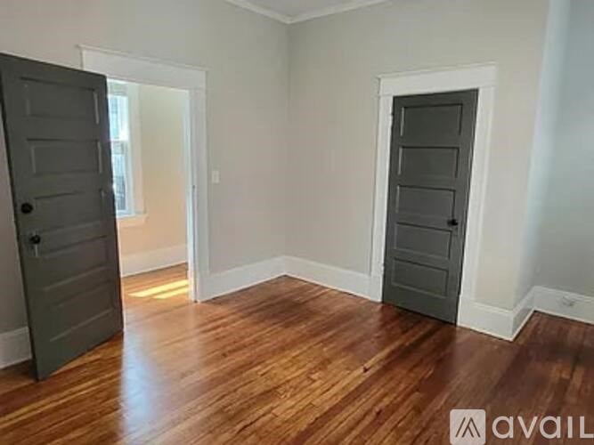 A room with wooden floors and two doors, one of which is open.