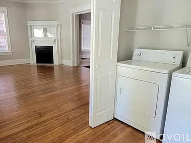 A white washer and dryer are sitting next to each other in a room with wood flooring.