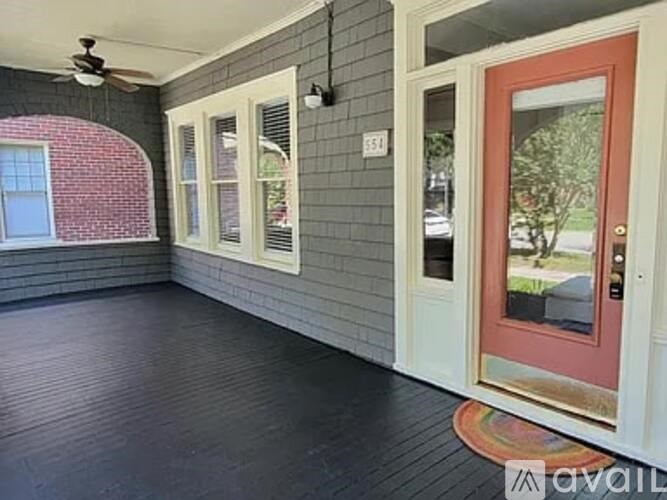 A room with a red door and a ceiling fan.