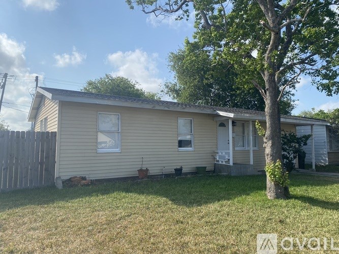 A beige house with a tree in front.