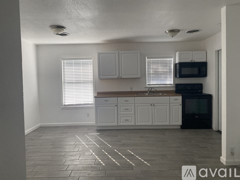 A kitchen with white cabinets and a black microwave.