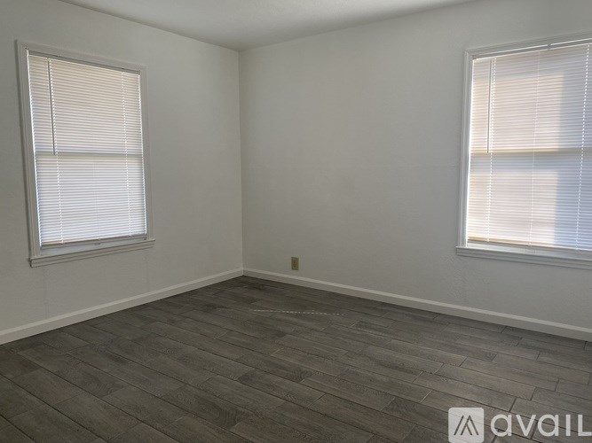 A room with two windows and a wooden floor.