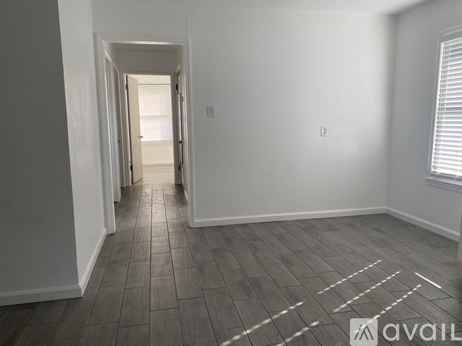 A hallway with wooden floors and white walls leading to a door.
