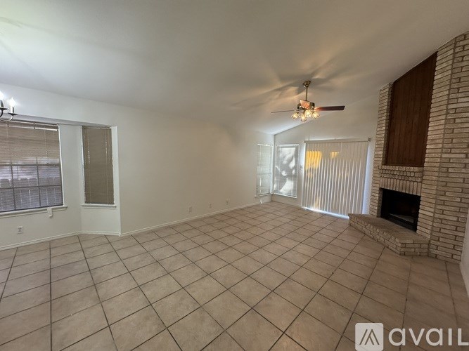 A spacious living room with a fireplace and a ceiling fan.