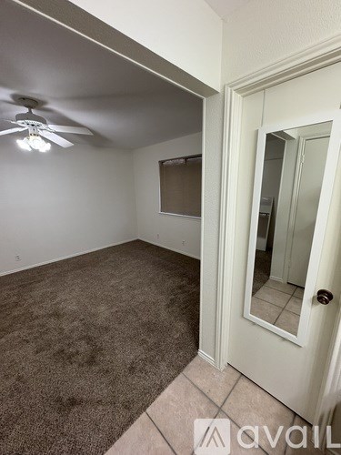 A room with a ceiling fan and a door leading to another room.