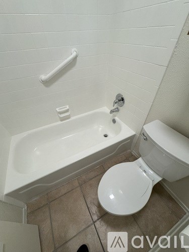 A white toilet sits next to a bathtub in a bathroom.