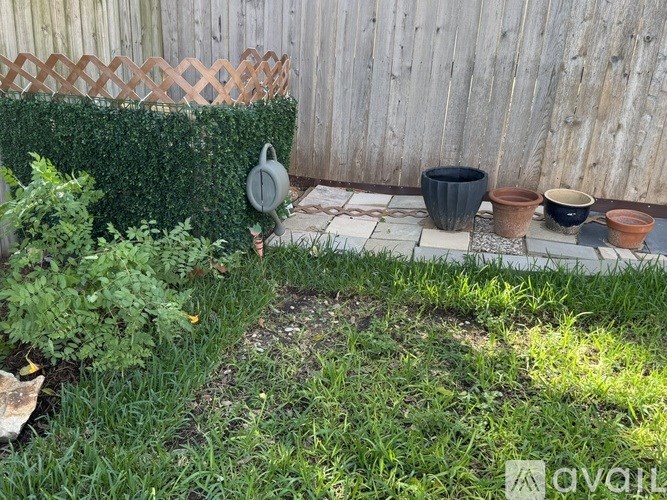 A garden with a fence, pots, and a plant.