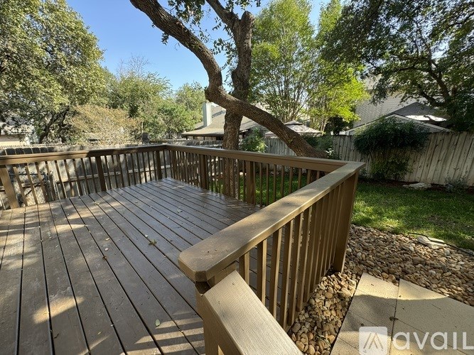 A wooden deck with a railing and a tree in the background.