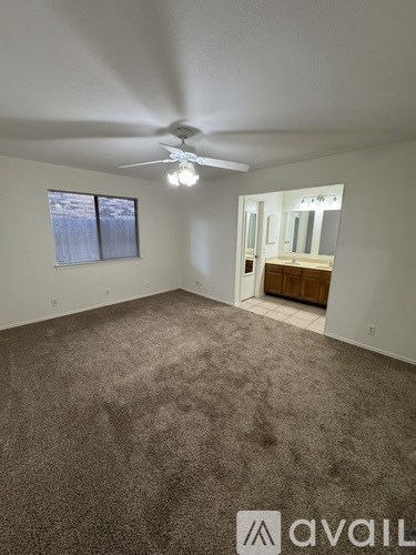 A backyard with a wooden deck, a fence, and a gravel path.
