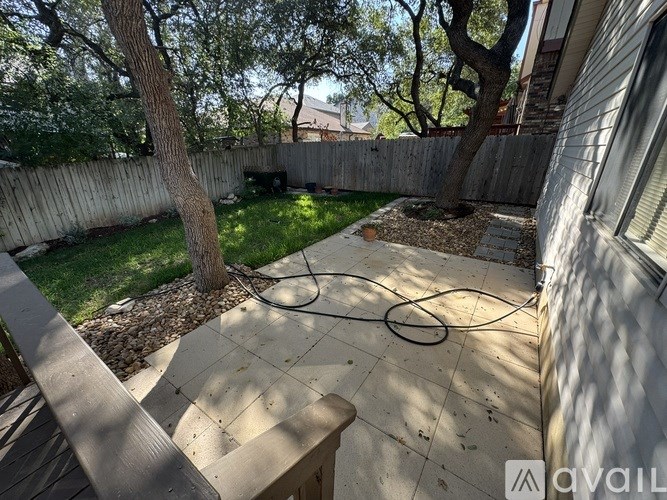 A backyard with a patio, a tree, and a fence.