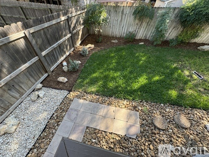 A backyard with a gravel area and a wooden fence.