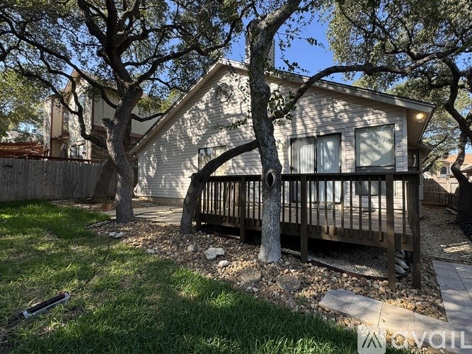 A tree in front of a house with a fence.