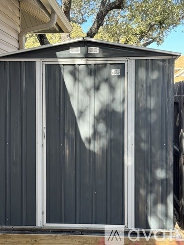 A grey shed with a white door and window.