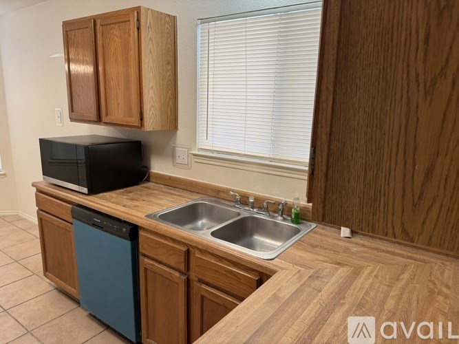 A kitchen with wooden cabinets and a black microwave.