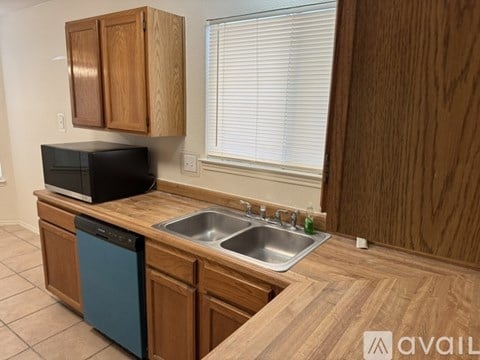 A kitchen with wooden cabinets and a black microwave.
