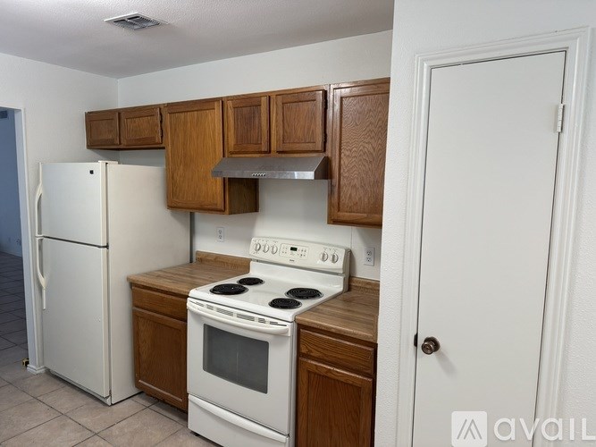 A kitchen with white appliances and wooden cabinets.