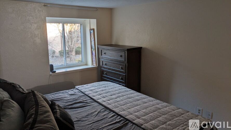 A bedroom with a bed, dresser, and window.