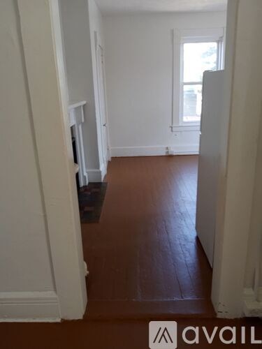 A hallway with a brown floor and white walls.