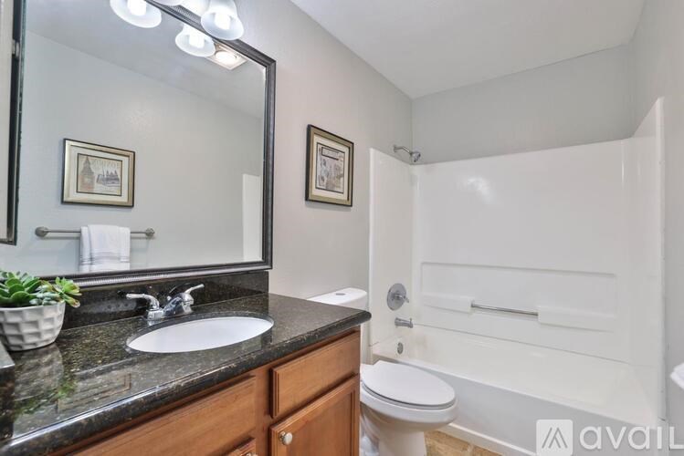 A bathroom with a sink, mirror, toilet, and bathtub.