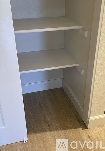 Empty white shelves in a corner of a room.