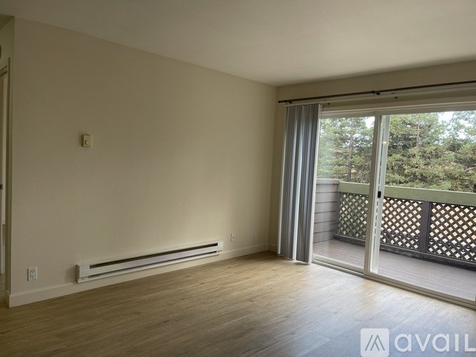 A room with a sliding glass door leading to a balcony with a view of trees.