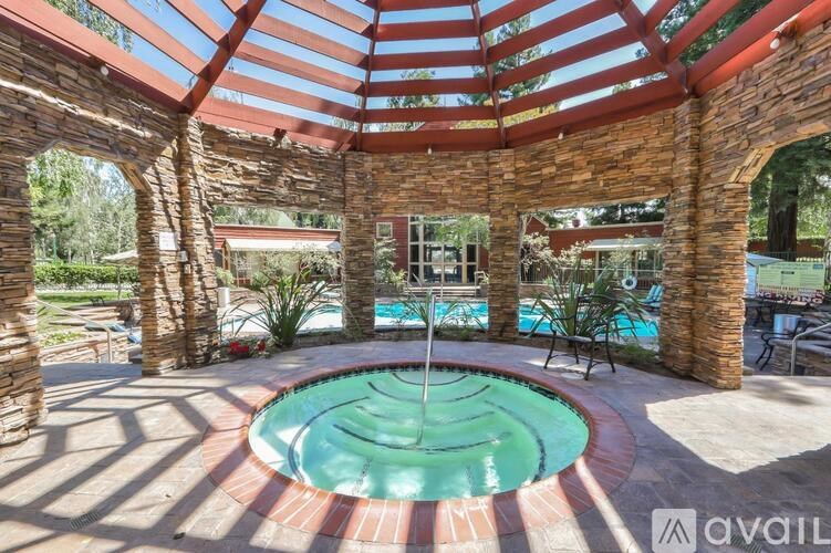 A pool surrounded by a stone wall and a roof.