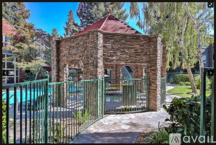 A small brick building with a gate in front of a pool.