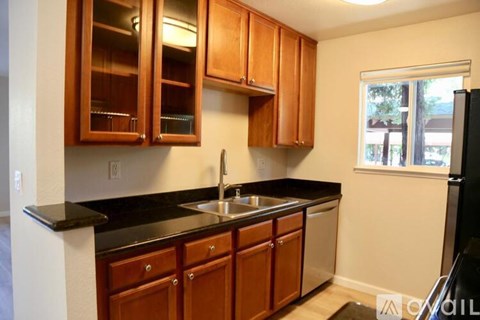A kitchen with wooden cabinets and black countertops.