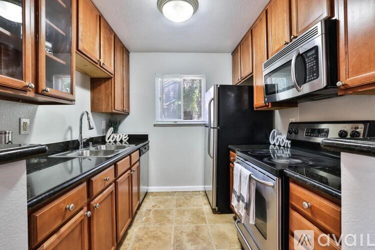 A kitchen with black appliances and wooden cabinets.